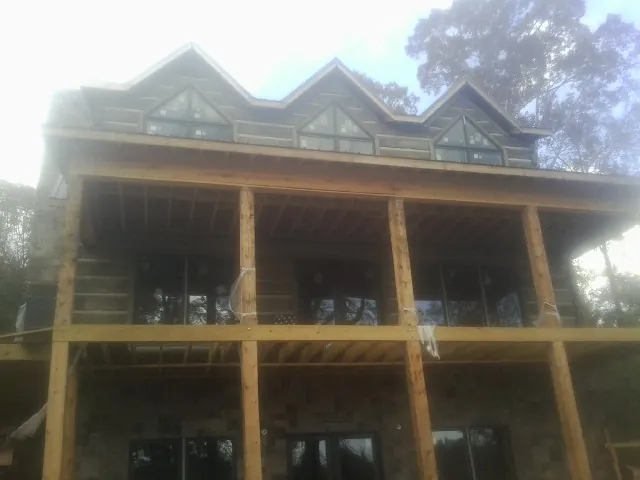 Dormers and porch framing on a large log home under construction — Roof Coating work by our crew in Holmes