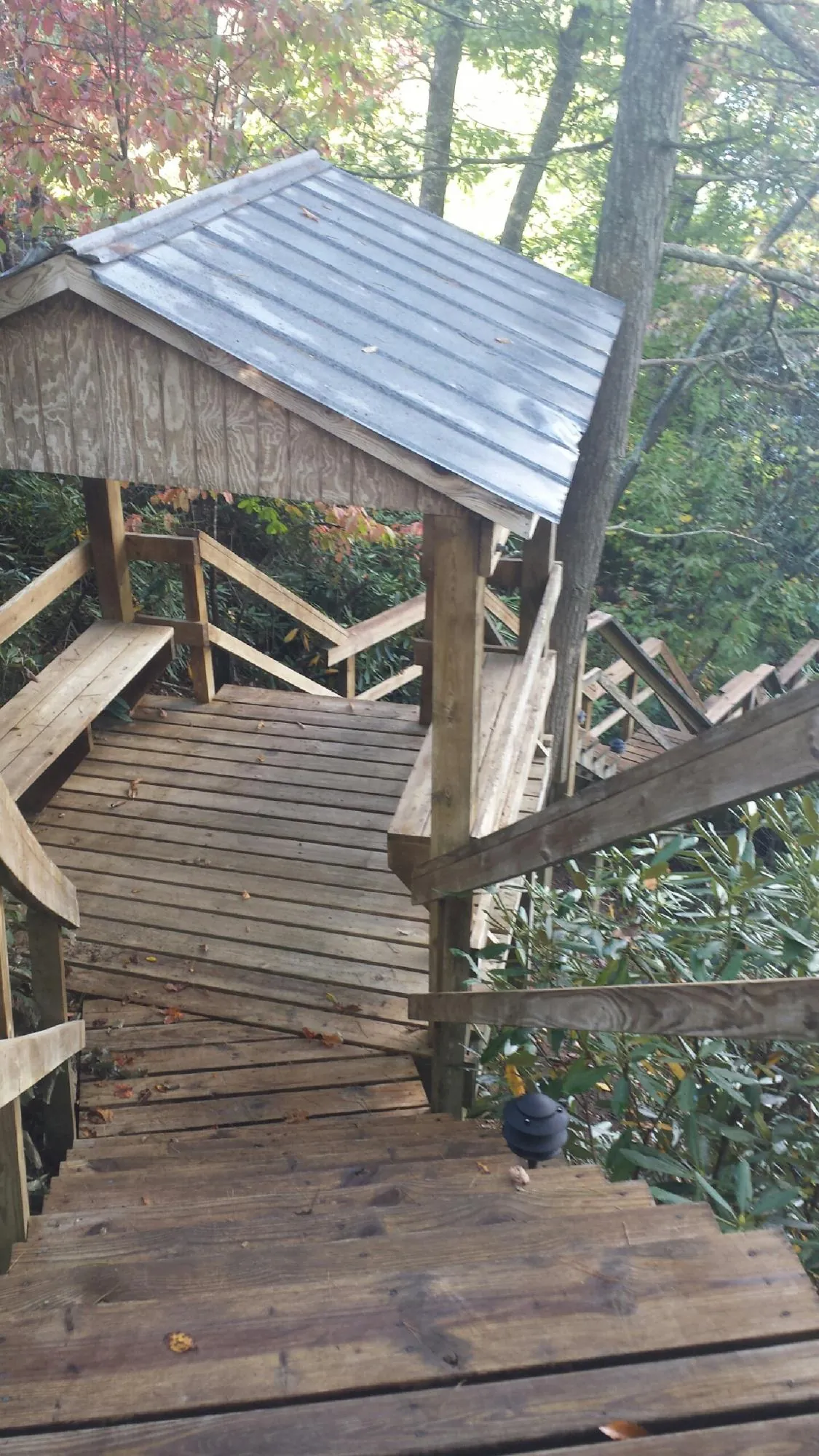 Metal roofed shelter over wooden steps on a wooded walkway — Skylight Repair & Installation work by our crew in Holmes